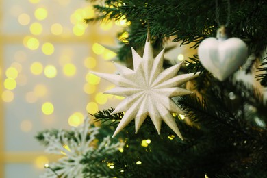 Photo of Closeup of beautiful bauble in shape of star hanging on Christmas tree. Space for text