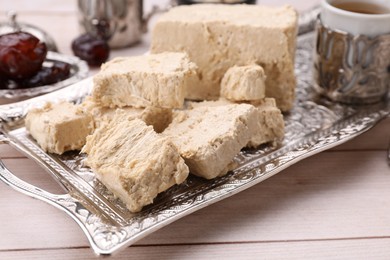 Pieces of tasty halva on light wooden table, closeup