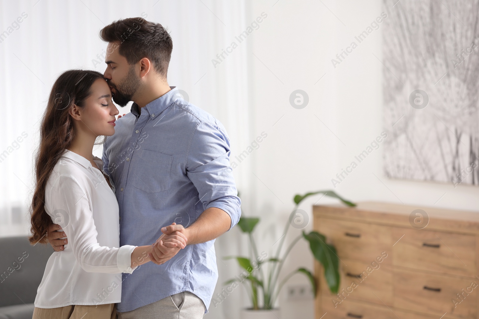 Photo of Cute couple. Man kissing his girlfriend at home, space for text