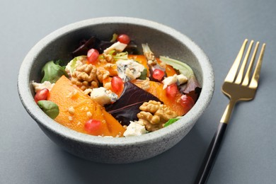 Delicious persimmon salad and fork on grey background