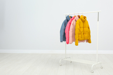 Photo of Rack with warm jackets in room. Space for text