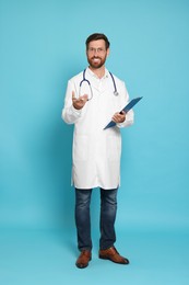 Photo of Full length portrait of doctor with stethoscope and clipboard on light blue background