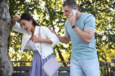 Man calling ambulance to help woman with heart attack in park