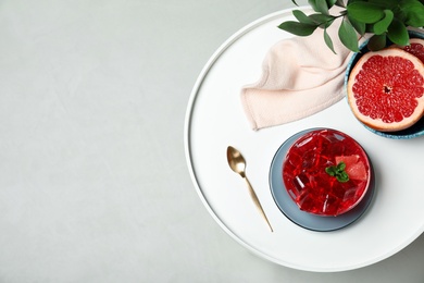 Photo of Flat lay composition with grapefruit jelly in bowl on light table. Space for text