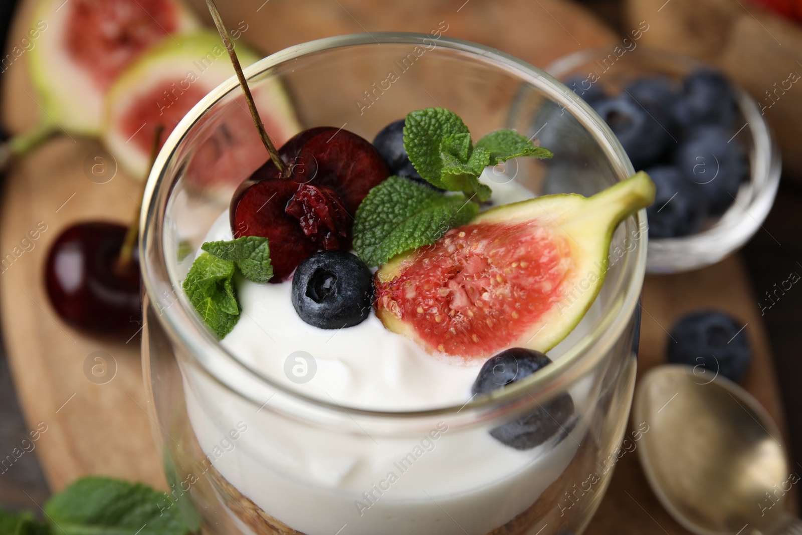 Photo of Glass with yogurt, berries and mint on table, closeup