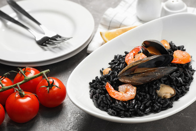 Photo of Delicious black risotto with seafood on marble table