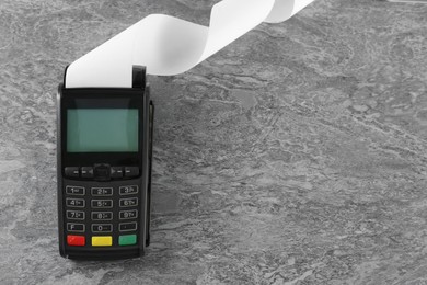 Photo of New modern payment terminal with blank paper bill on grey table, top view. Space for text