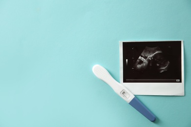 Photo of Ultrasound picture of baby and pregnancy test on color background, top view with space for text