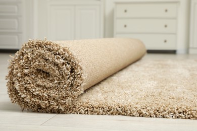 Photo of Rolled beige carpet on floor, closeup. Space for text