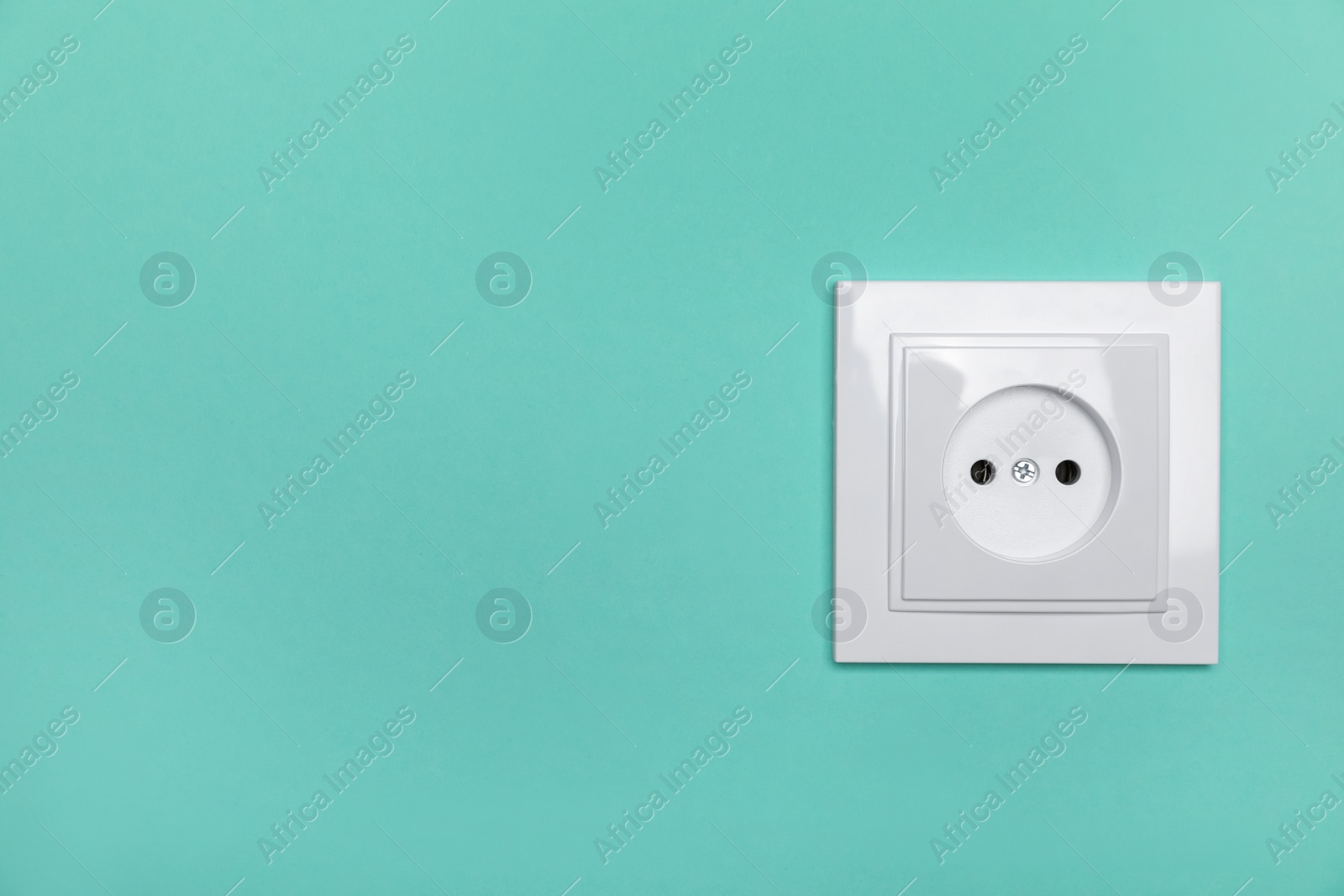 Photo of Power socket on turquoise wall, space for text. Electrical supply
