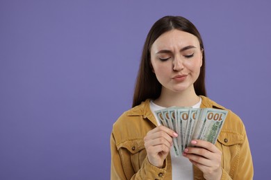 Woman with dollar banknotes on purple background, space for text