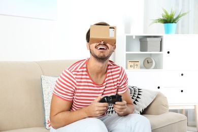 Young man using cardboard virtual reality headset at home