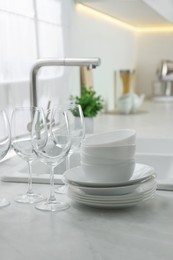 Photo of Different clean dishware and glasses on countertop near sink in kitchen