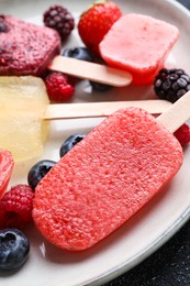 Photo of Plate of different tasty ice pops on table, closeup. Fruit popsicle