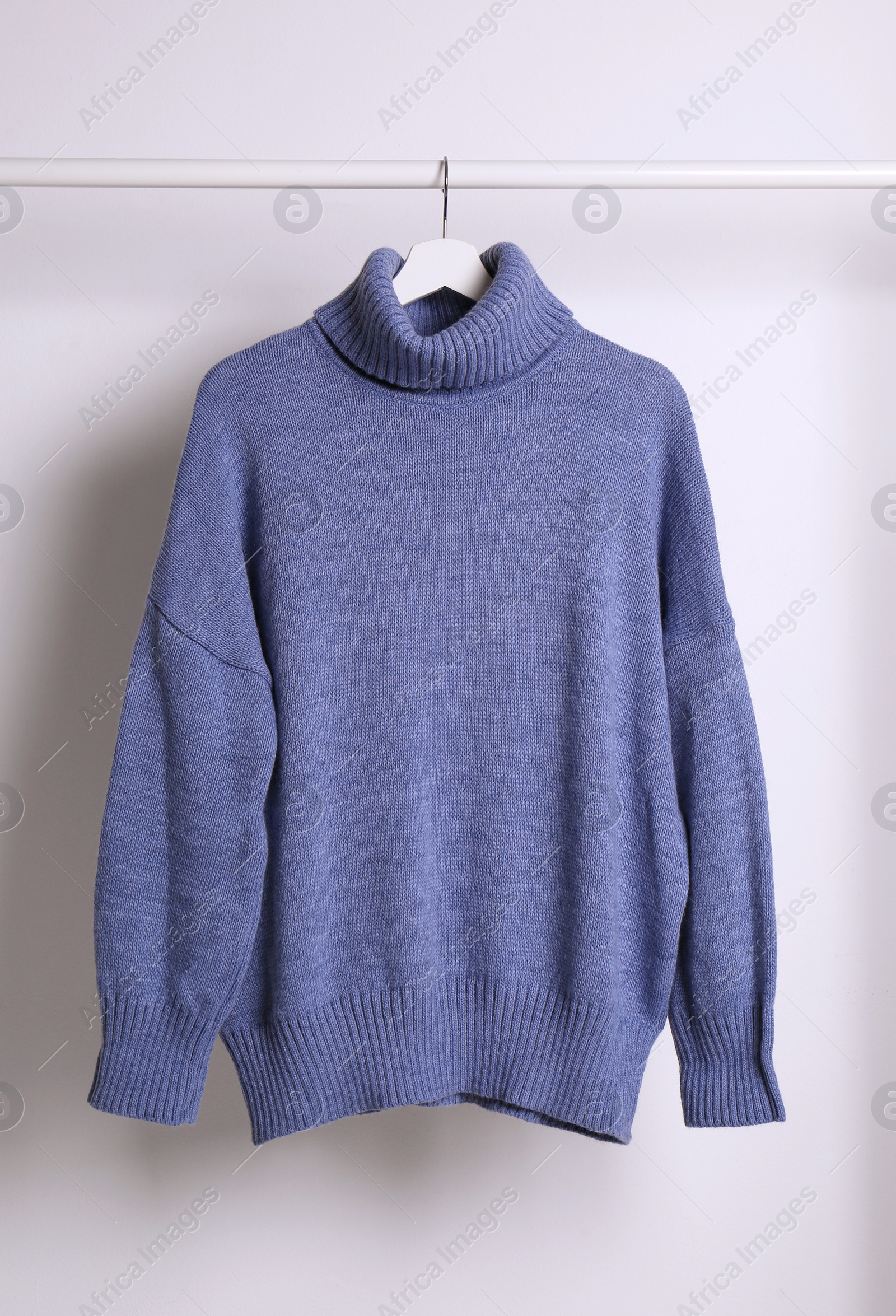 Photo of Warm sweater hanging on rack against white background