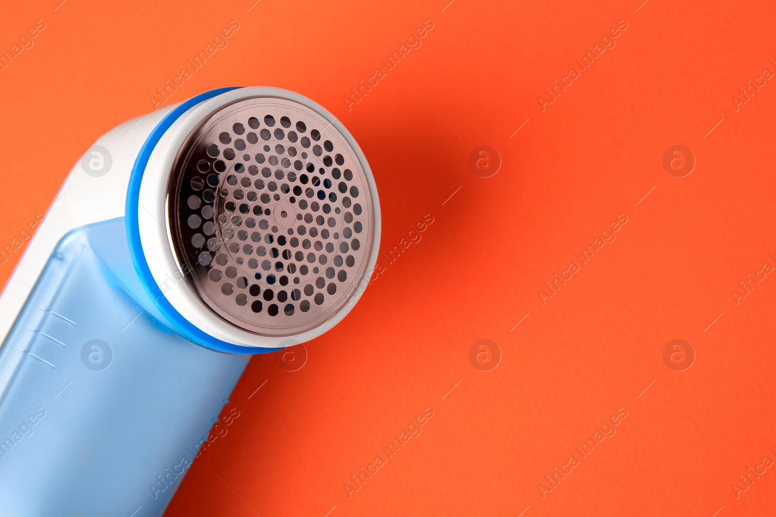 Photo of Fabric shaver on orange background, closeup. Space for text