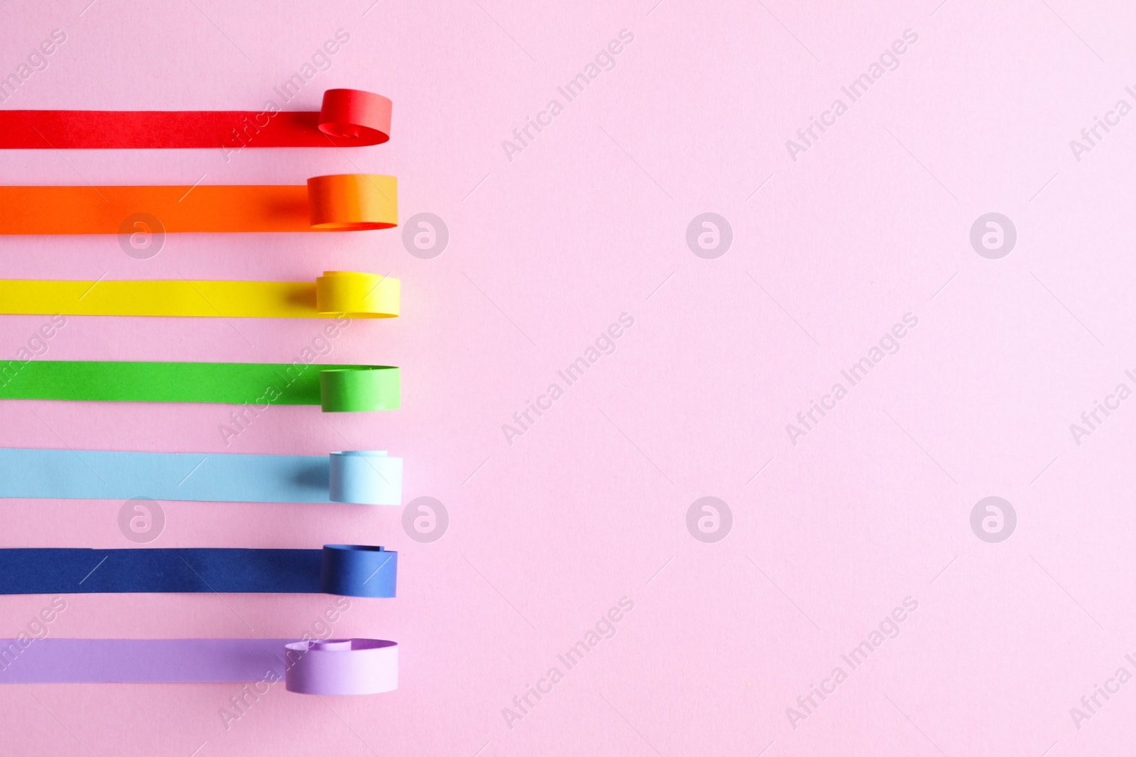 Photo of Bright paper strips and space for text on pink background, flat lay. Rainbow colors