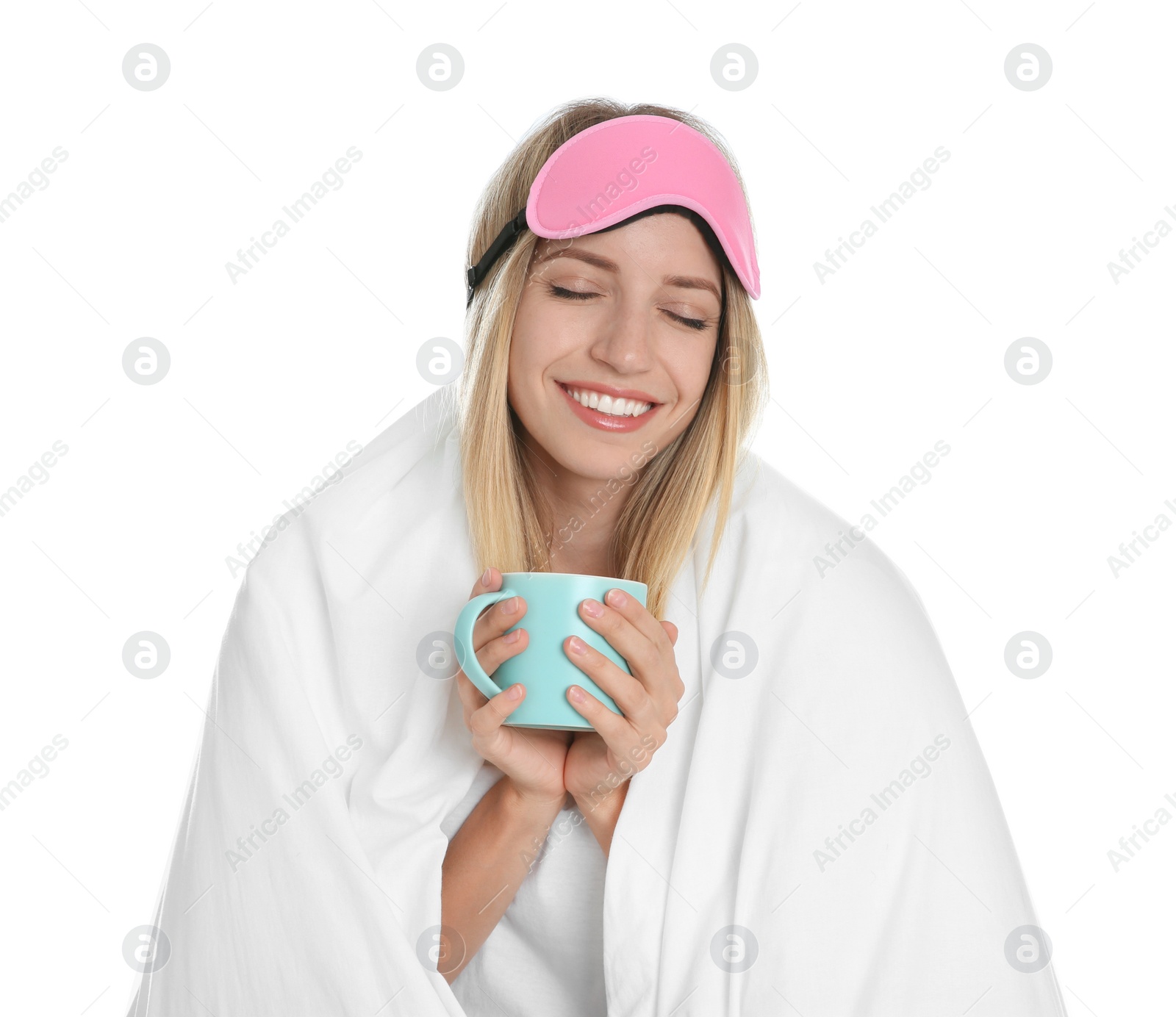 Photo of Happy woman in sleeping mask wrapped with blanket holding cup on white background