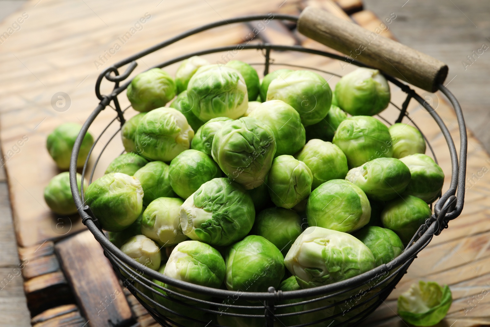 Photo of Metal basket with fresh Brussels sprouts on table, closeup