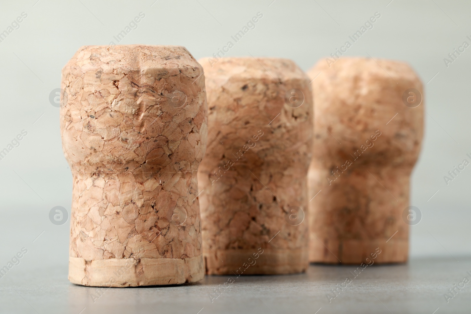 Photo of Corks of wine bottles on light grey table, closeup