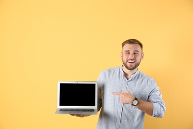 Photo of Young man with laptop on color background