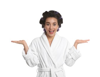 Photo of Emotional young woman in bathrobe with hair curlers on white background