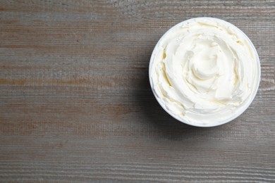 Photo of Bowl of tasty cream cheese on wooden table, top view. Space for text