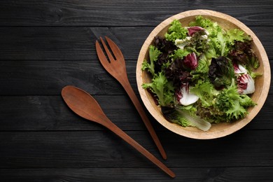 Salad made with different sorts of lettuce served on black wooden table, flat lay