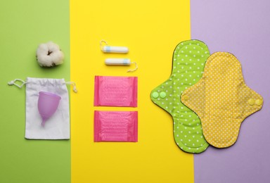 Photo of Cloth menstrual pad near other reusable and disposable female hygiene products on color background, flat lay