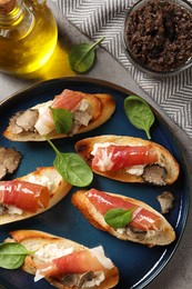 Photo of Delicious bruschettas with cheese, prosciutto and slices of black truffle on grey table, flat lay