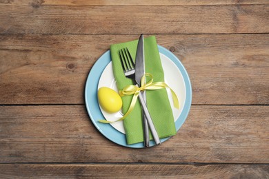 Photo of Festive table setting with painted egg and cutlery, top view. Easter celebration