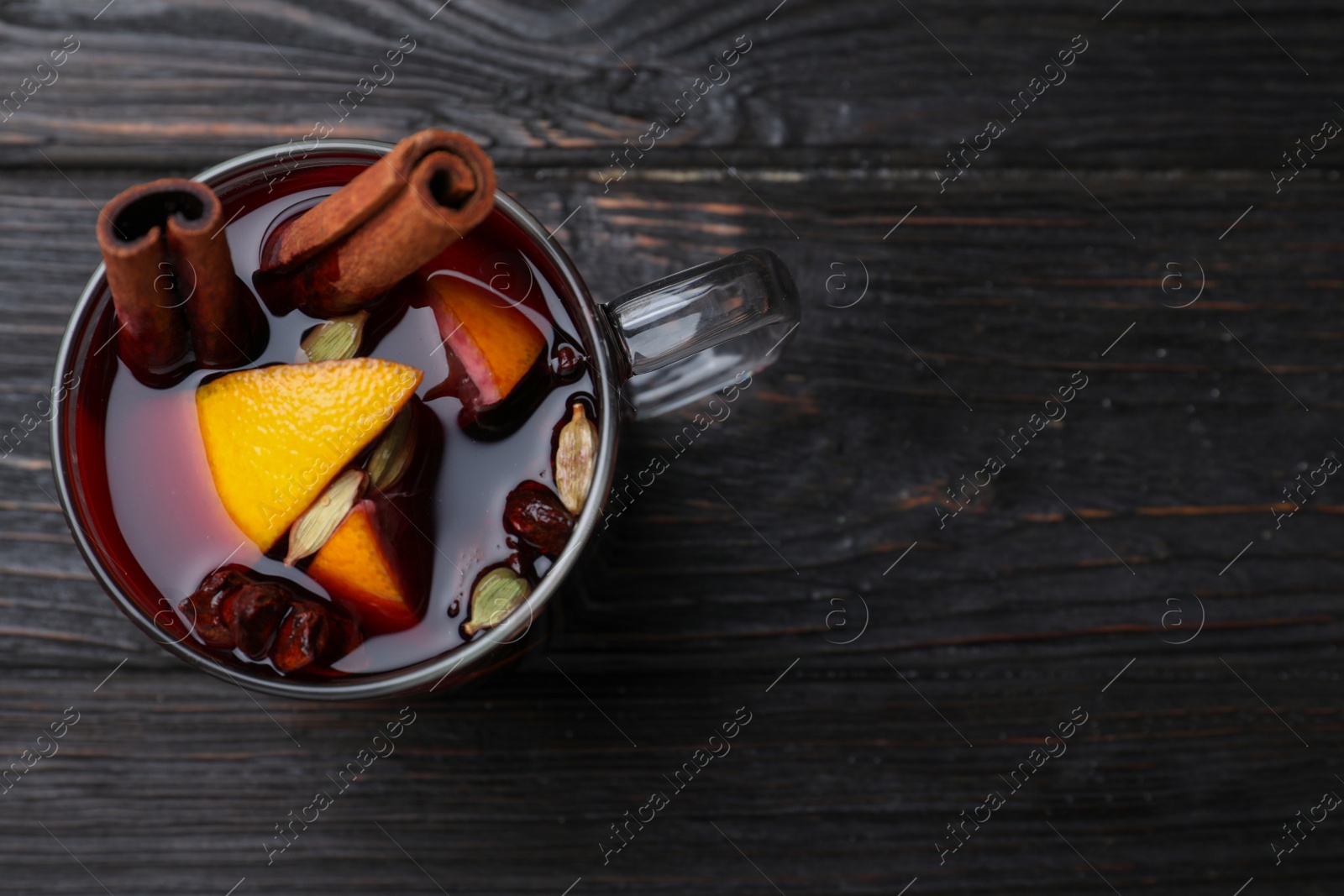 Photo of Aromatic mulled wine on wooden table, top view. Space for text