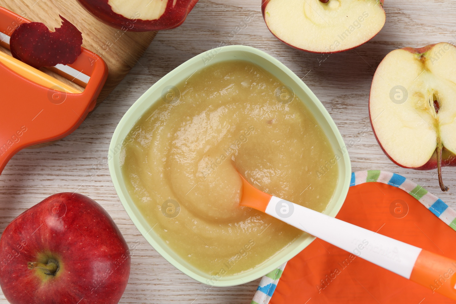 Photo of Healthy baby food. Bowl with delicious apple puree and fresh fruits on white wooden table, flat lay