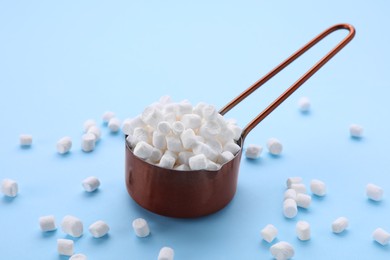 Photo of Scoop with delicious marshmallows on light blue background