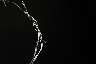 Photo of Metal barbed wire on black background. Space for text