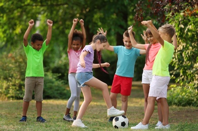 Cute little children playing with soccer ball in park