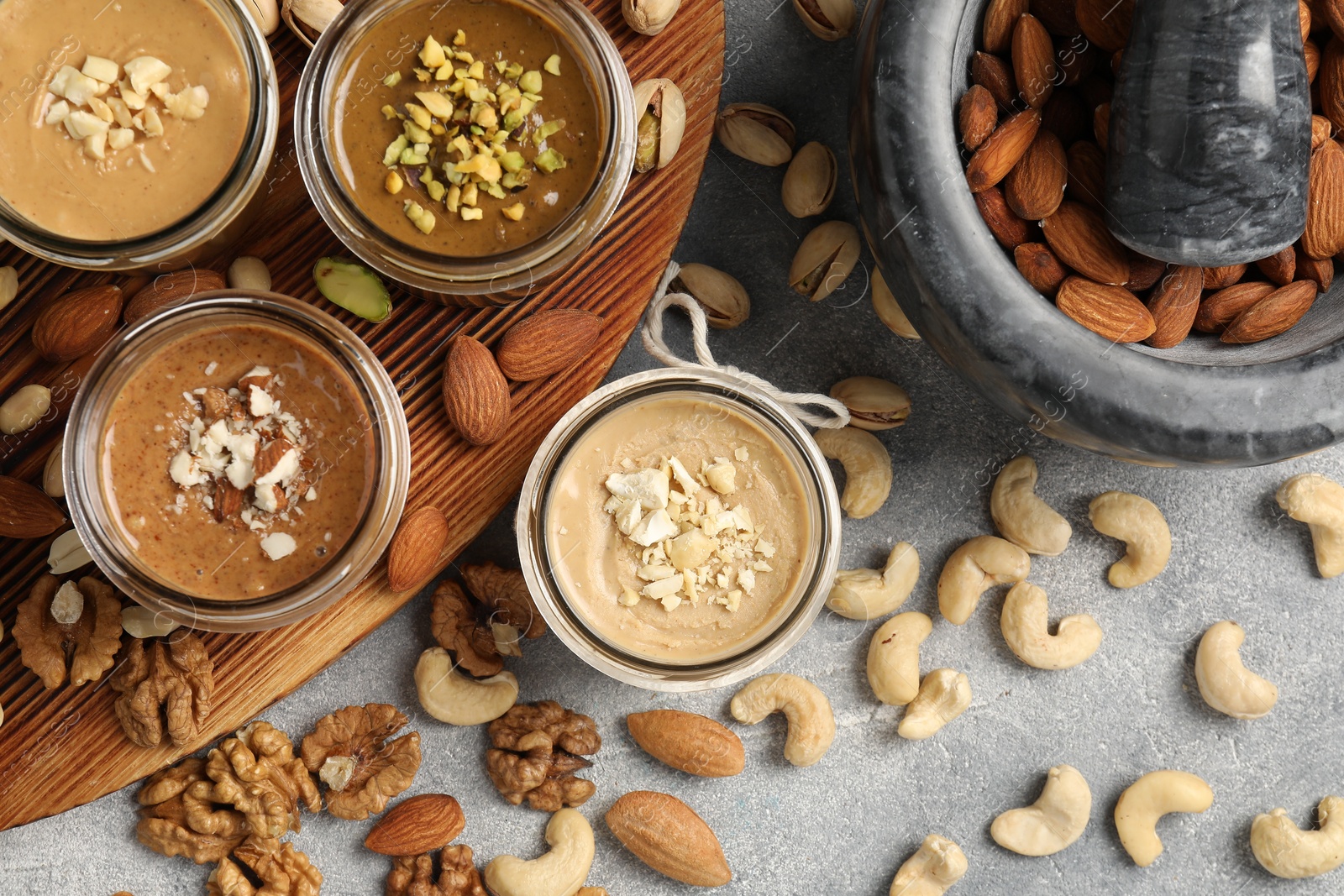 Photo of Making nut butters from different nuts. Flat lay composition on light grey table