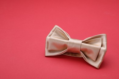 Photo of Stylish beige bow tie on red background, space for text
