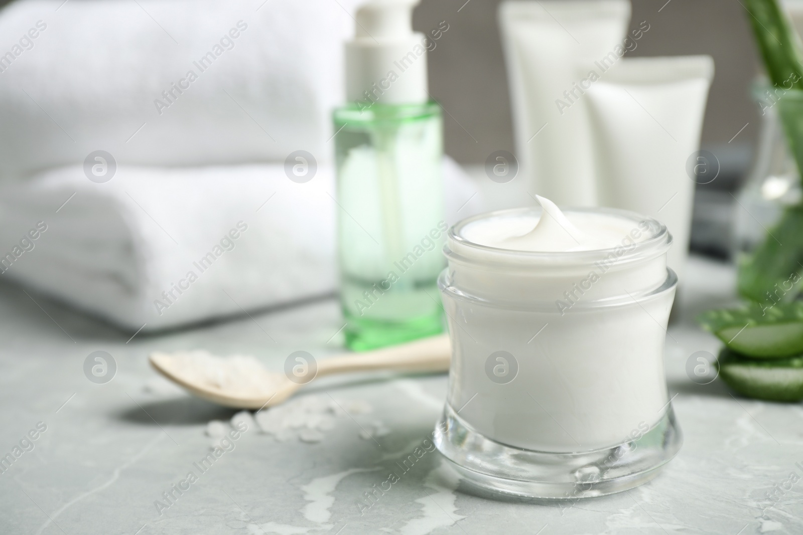 Photo of Open jar of aloe cream on grey marble table. Organic cosmetics