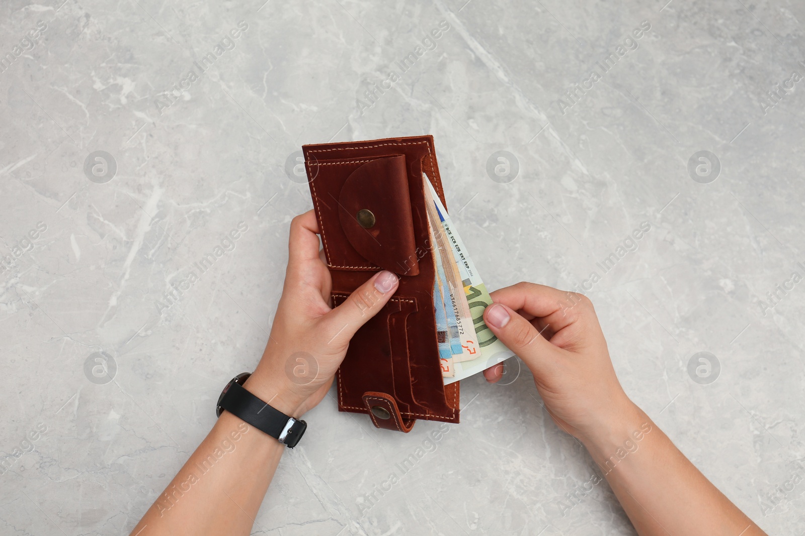 Photo of Man putting Euro banknotes in wallet, top view