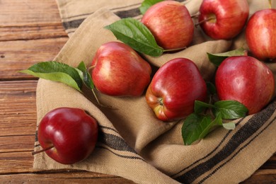 Photo of Ripe red apples with leaves on wooden table