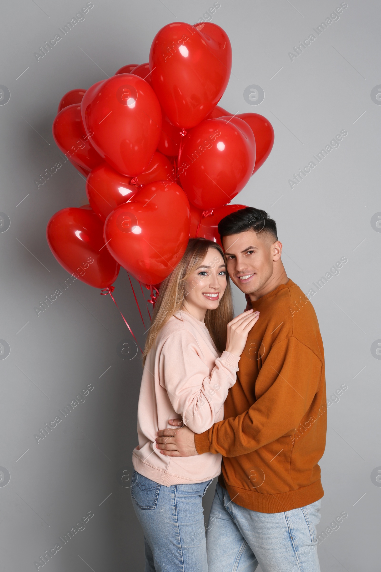 Photo of Lovely couple with heart shaped balloons on grey background. Valentine's day celebration