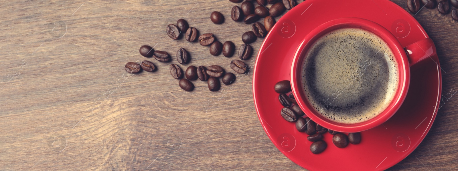 Image of Cup of aromatic coffee and beans on wooden table, top view with space for text. Banner design