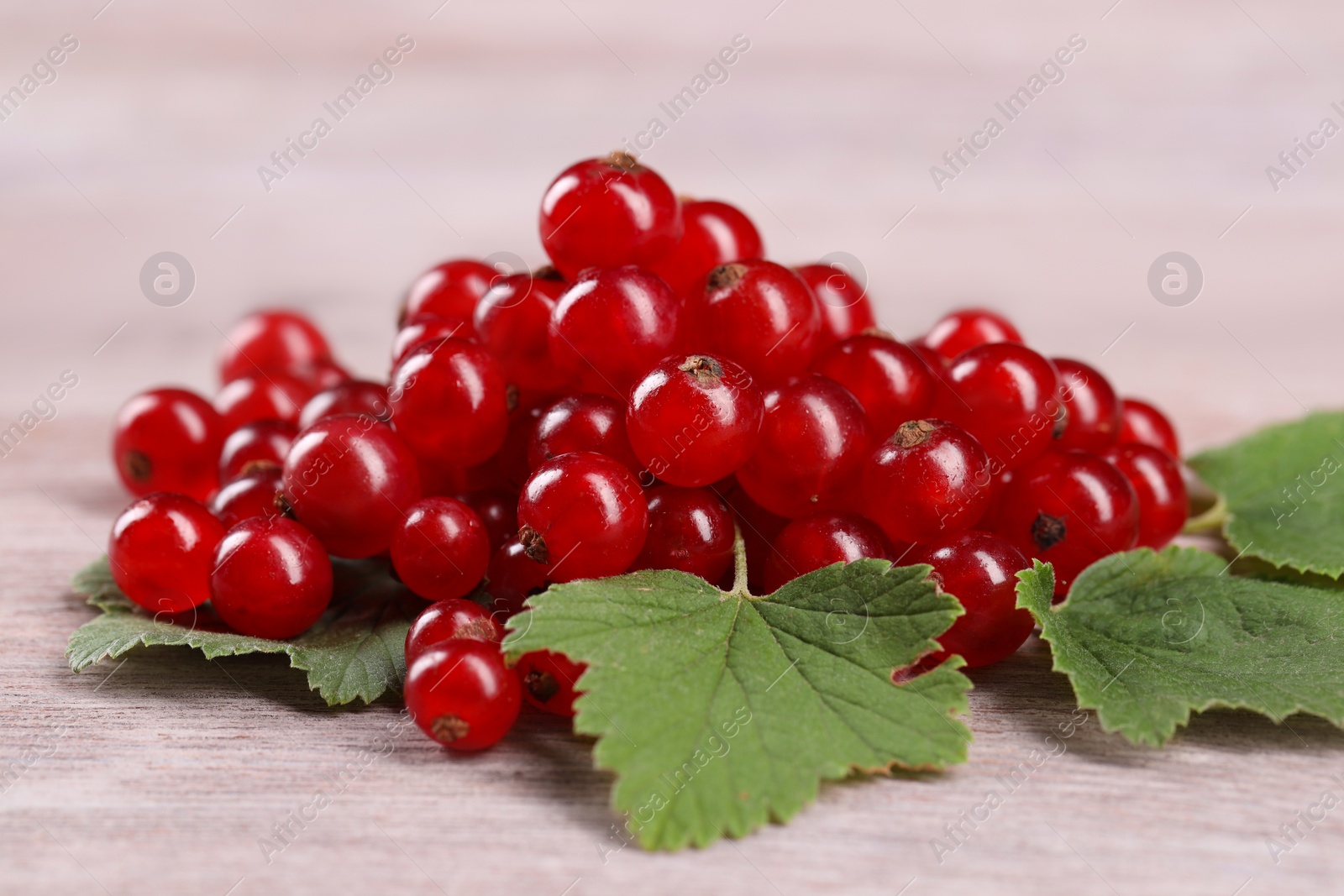 Photo of Ripe red currants on light wooden table, closeup
