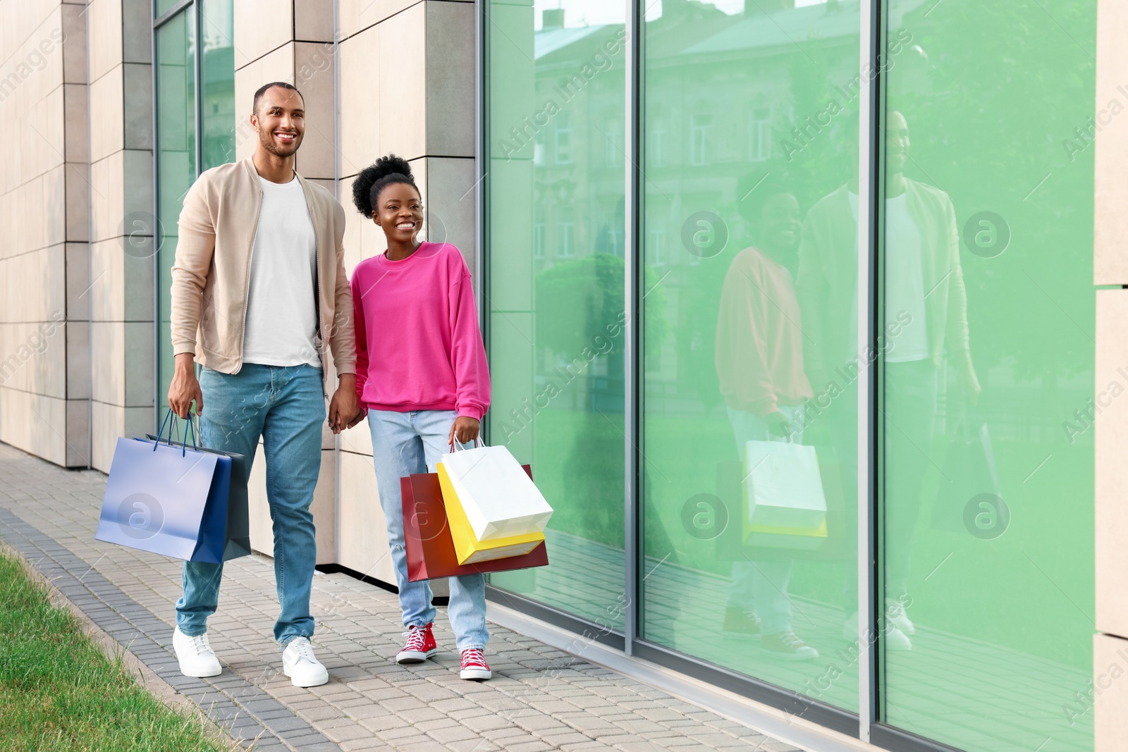 Photo of Family shopping. Happy couple with colorful bags near mall outdoors