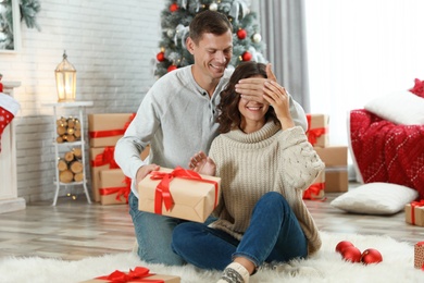 Man presenting Christmas gift to his girlfriend at home 