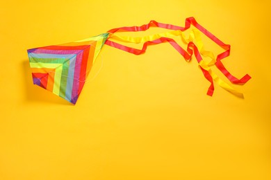 Photo of Bright rainbow kite on yellow background, top view. Space for text