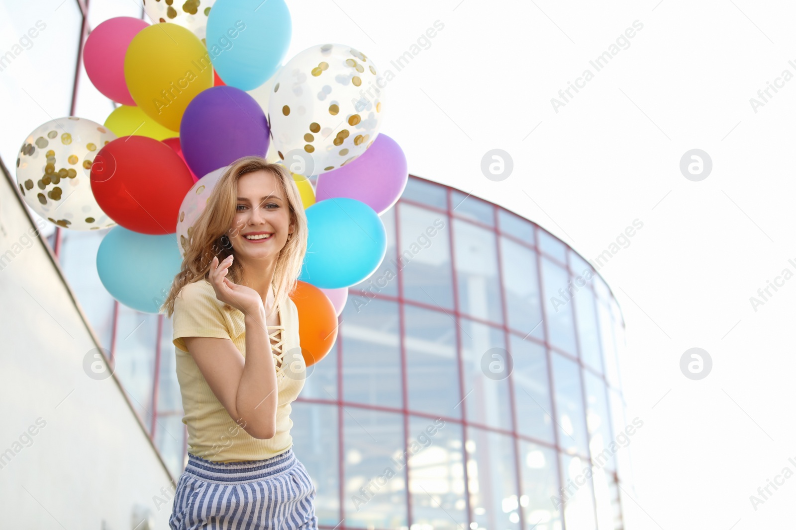 Photo of Young woman with colorful balloons outdoors on sunny day