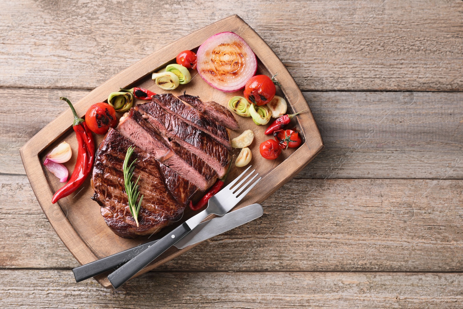 Photo of Delicious fried beef meat served with vegetables on wooden table, top view. Space for text