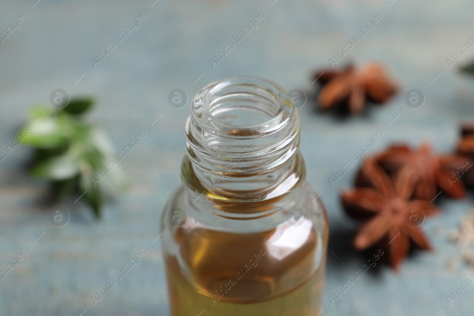 Photo of Anise essential oil in bottle on table, closeup